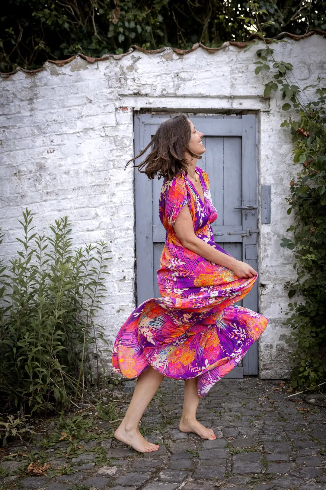 Caroline Bertrand tourbillonnant dans sa robe colorée devant une porte bleue