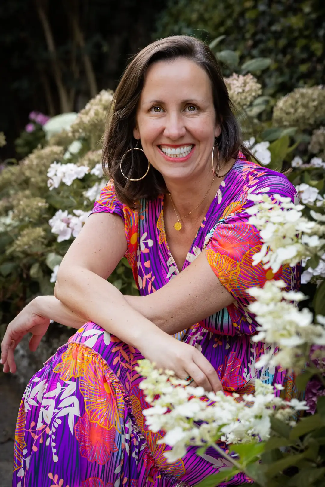 Caroline Bertrand, souriante, en robe colorée, dans un jardin fleuri